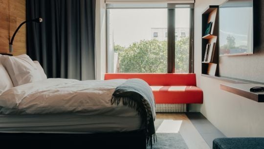 Minimalist Icelandic hotel room with sleek Nordic design, crisp white linens, modern wood furnishings, and expansive window showcasing urban landscape