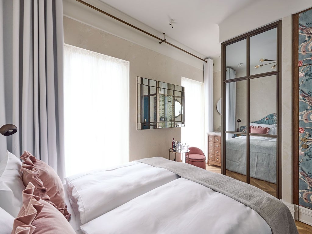 Elegant modern hotel room with minimalist design, crisp white bedding, sleek wooden furniture, and large window overlooking urban Austrian landscape at dusk