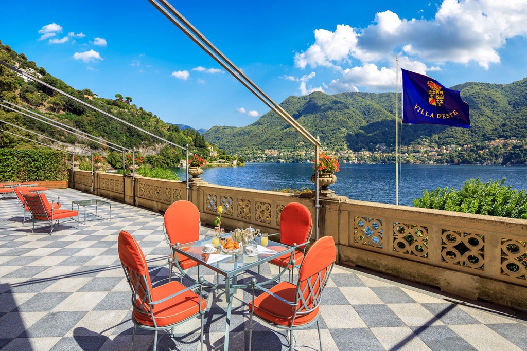 Historic luxury Italian villa with ornate Renaissance gardens, cascading terraces, and water features overlooking Lake Como at sunset