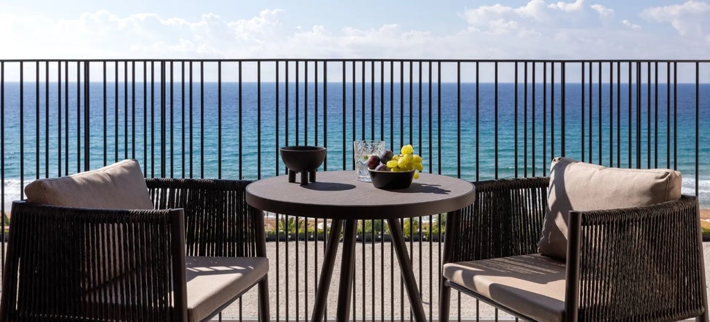 Luxurious Patio Junior Suite with elegant white decor, sea view terrace, and minimalist design overlooking azure Corfu landscape and sparkling Mediterranean waters