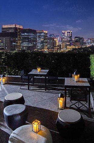 Luxurious hotel room with elegant twin/king bed, modern decor, and floor-to-ceiling windows overlooking Wadakura Fountain Park in Tokyo, Japan.