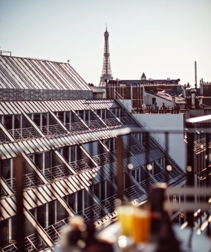 Elegant Parisian hotel exterior with refined stone facade, large windows, and chic awnings, showcasing luxurious boutique hotel ambiance at dusk