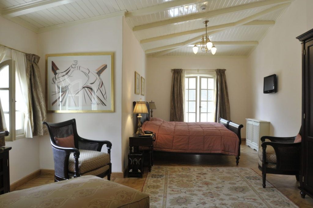 Elegant colonial mansion with palm-lined courtyard, white balconies, and Art Nouveau architecture in a lush Cairo neighborhood