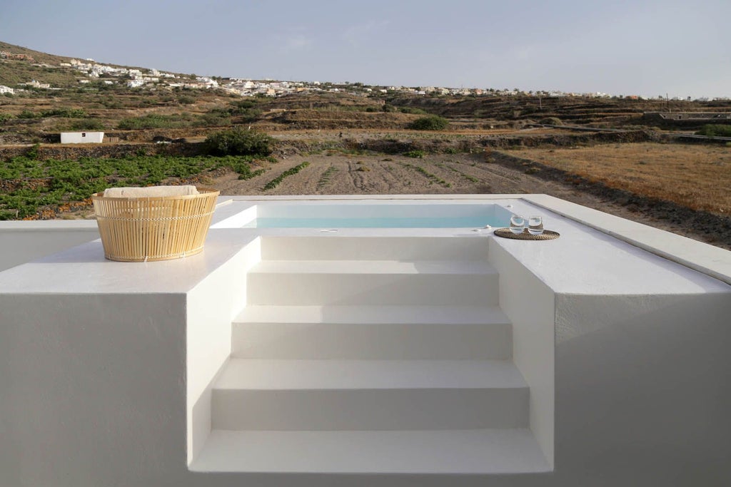 Luxury boutique white-washed Greek villa with blue shutters overlooking azure Aegean Sea, nestled among rolling vineyards at sunset in picturesque scenset landscape