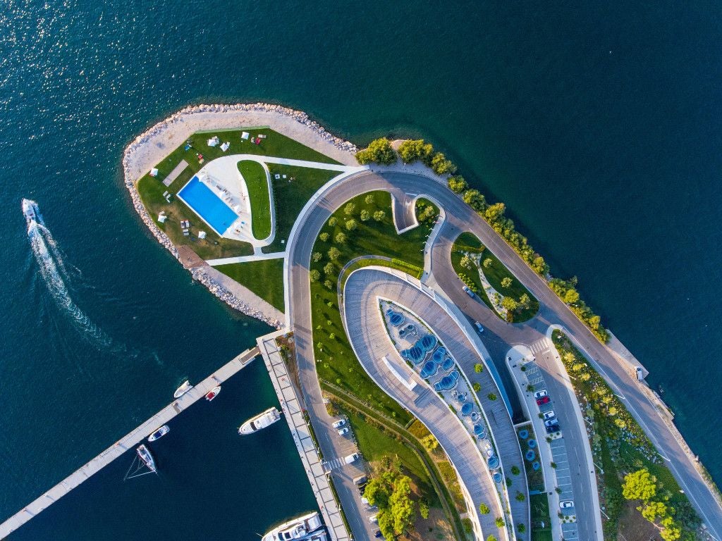 Luxurious coastal resort with modern white architecture overlooking azure Adriatic waters, nestled against scenic rocky Croatian landscape near Šibenik.