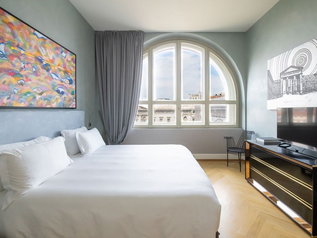 Luxurious deluxe room at Scenset Hotel Milano, featuring elegant Italian design with modern art, plush bedding, and expansive city view windows