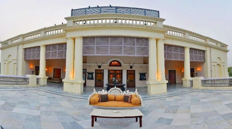 Historic luxury hotel Taj Nadesar Palace features white colonial architecture with ornate pillars surrounded by manicured gardens and palm trees