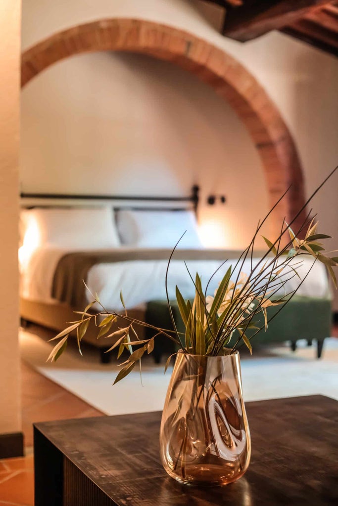 Rustic stone walls and terracotta tilework adorn an exclusive boutique hotel nestled in the Tuscan countryside with cypress trees and a pool