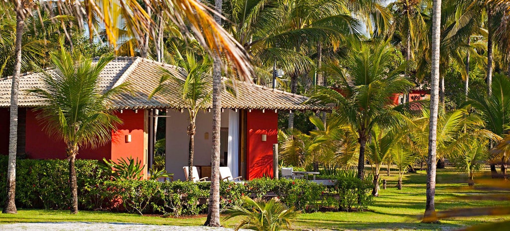 Luxurious Brazilian beachfront bungalow with wooden deck, minimalist design, tropical foliage, and panoramic ocean view at sunset