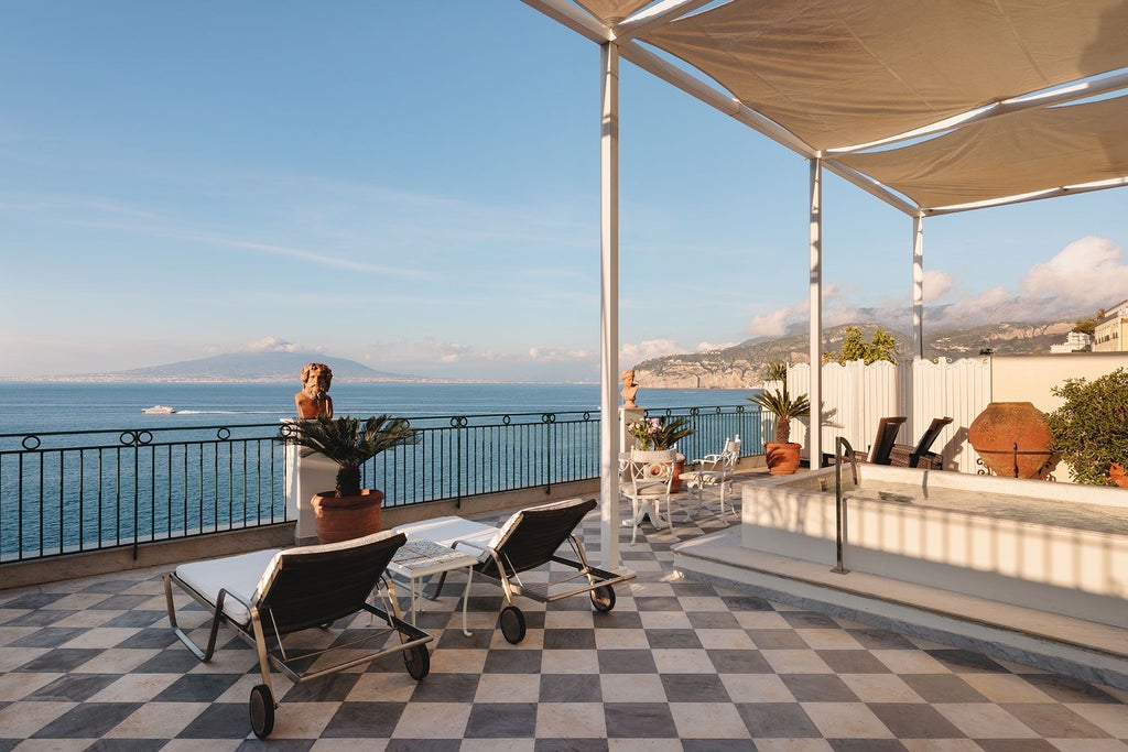 Elegant marble-clad suite with panoramic Sorrento coastline views, plush white bedding, and ornate crystal chandelier in luxurious Lord Astor accommodation