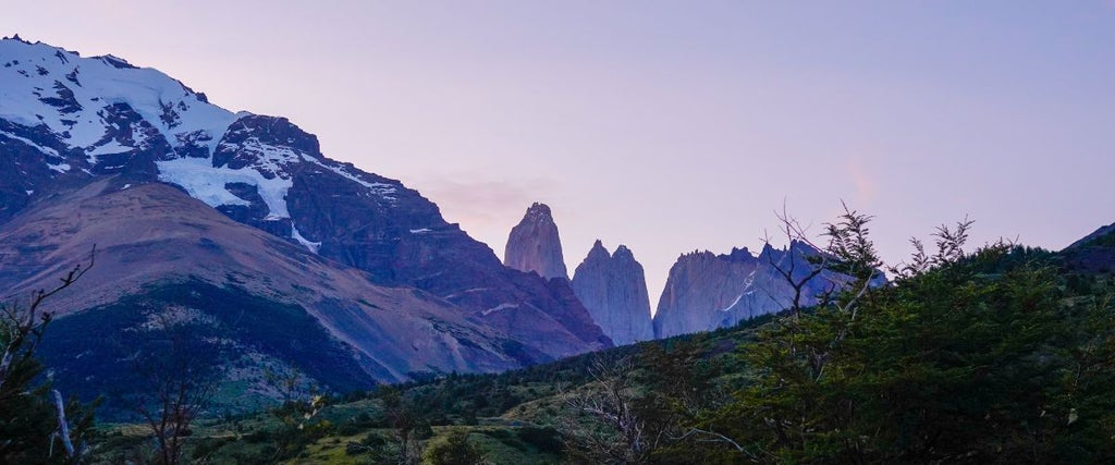 Cozy mountain hostel room with rustic wooden furniture, panoramic Patagonian landscape view, warm lighting, and minimalist alpine-inspired design elements.