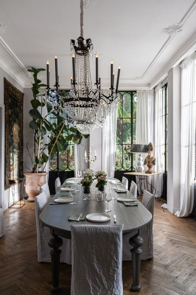 Historic French boutique hotel with elegant stone facade, arched windows, ornate iron balconies and lush ivy climbing the walls