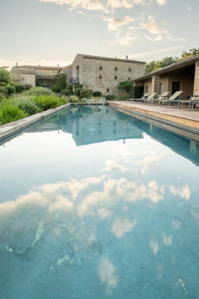 Elegant stone facade of restored 16th-century farmhouse, soft golden light, lavender fields, rustic Provence charm at boutique hotel La Maison d'Ulysse