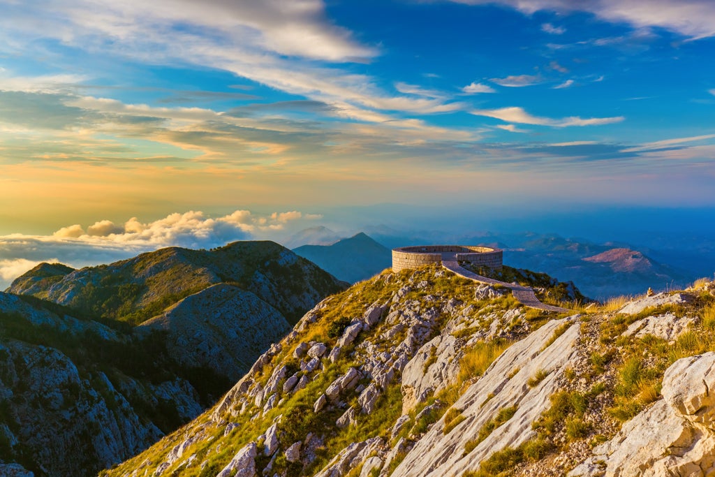 Rugged Montenegrin mountain landscape with winding road, pristine alpine terrain, luxury convertible car navigating scenic mountain pass at golden hour