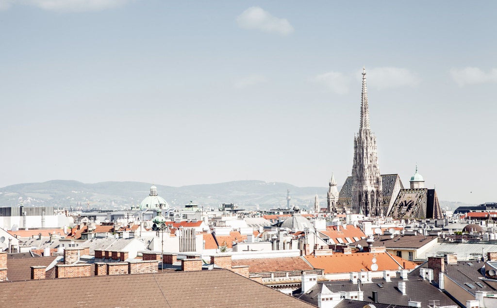 Elegant 19th-century Viennese luxury hotel with marble facade, grand windows, and neoclassical architectural details overlooking a picturesque Austrian streetscape.