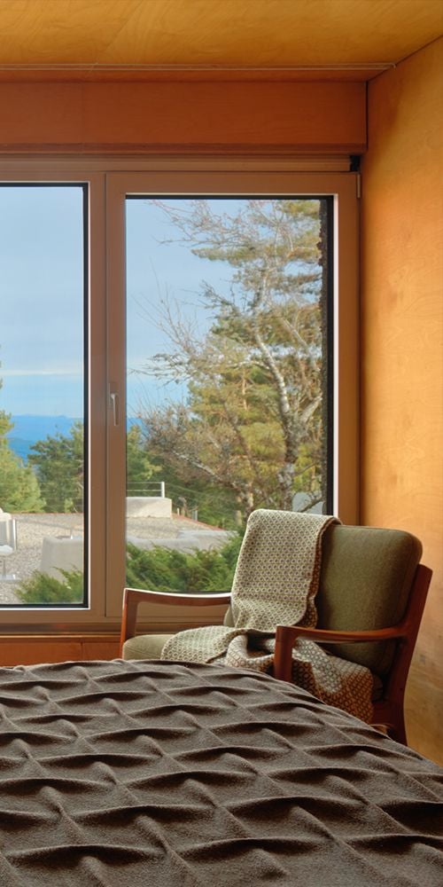 Elegant mountain-view double room at Casa das Penhas Douradas, featuring crisp white linens, warm wood accents, and panoramic Portuguese landscape