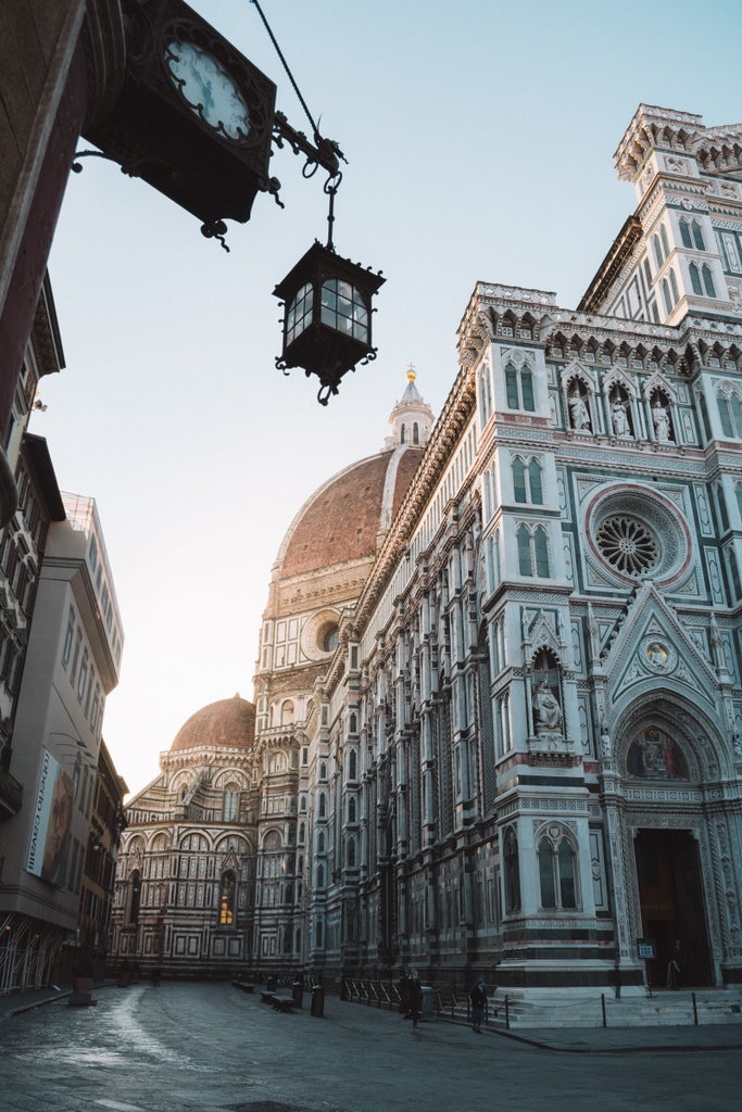 Panoramic view of Florence at sunset, featuring iconic Duomo cathedral and red-tiled rooftops stretching across historic cityscape