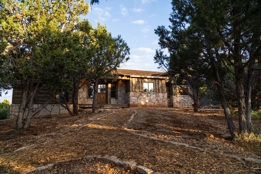 Rustic wooden lodge room with panoramic mountain views, plush bedding, and warm timber accents at a scenic wilderness retreat near a national park.