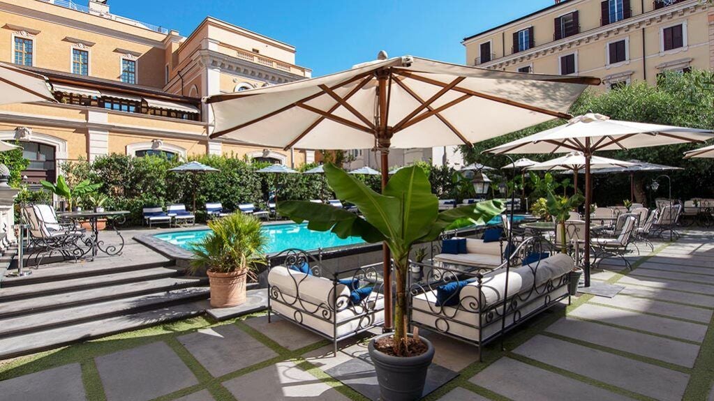 Elegant marble facade of luxury boutique hotel overlooking historic Rome, with sleek outdoor terrace and classic Italian architectural details at sunset