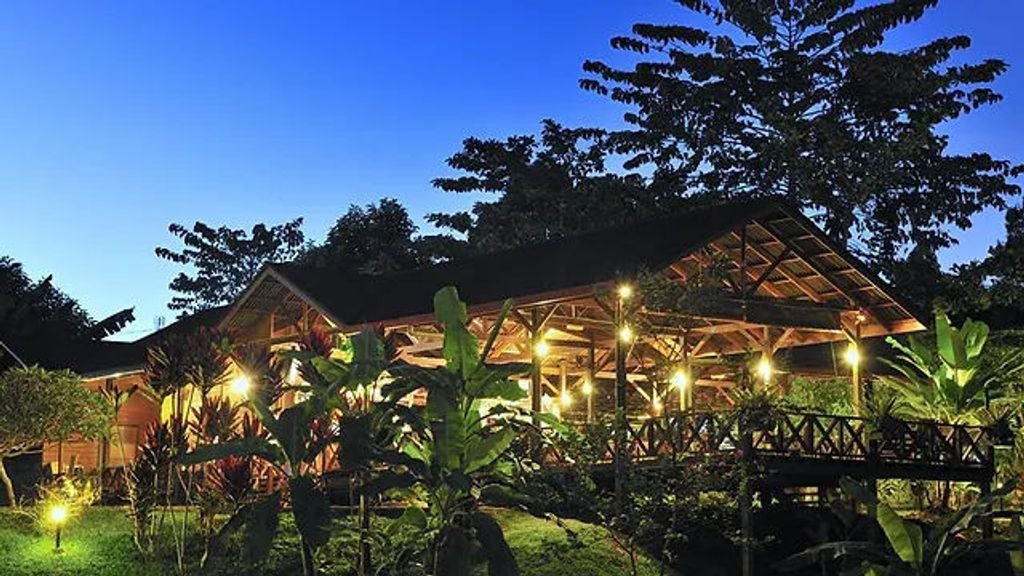 Luxurious wooden chalets nestled in lush Malaysian rainforest, connected by elevated walkways with tropical landscaping