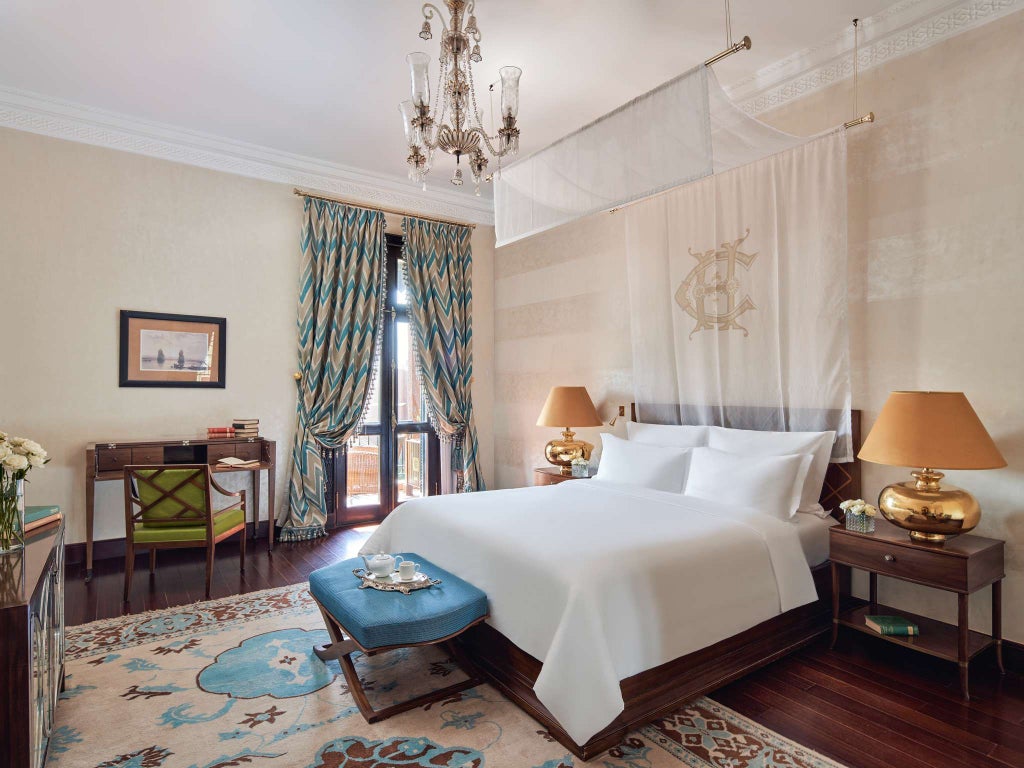 Luxurious palace-style hotel room with plush king-size bed overlooking lush garden, featuring elegant Sofitel design in historic Aswan, Egypt