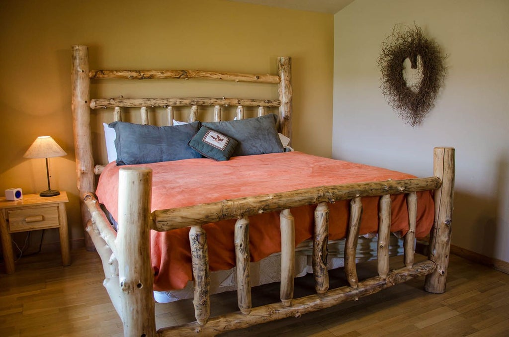 Rustic wooden cabin bedroom with plush bedding, panoramic mountain views, and warm, inviting decor in a serene Zion National Park landscape