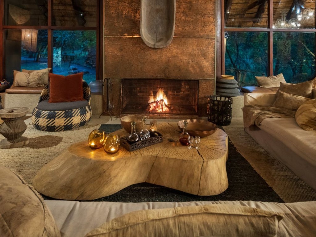 Luxurious private deck with plunge pool overlooking African bush, featuring thatched roof lodge and natural stone walls.