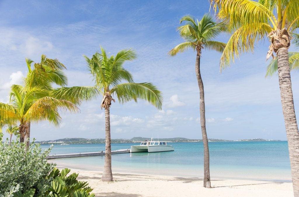 Luxurious beachfront resort on a pristine white sandy beach, crystal-clear turquoise waters, and lush tropical landscape at Scenset Bay Island, Antigua