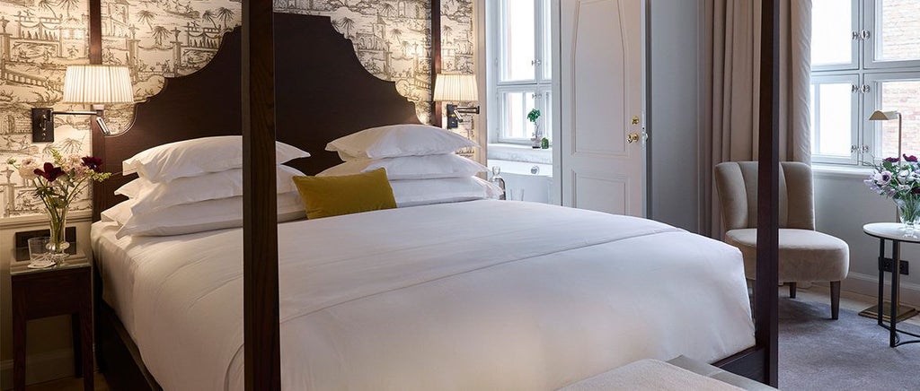 Elegant Scandinavian-style deluxe hotel room with plush white bedding, modern wood furnishings, and soft neutral color palette in Hotel Villa Dagmar