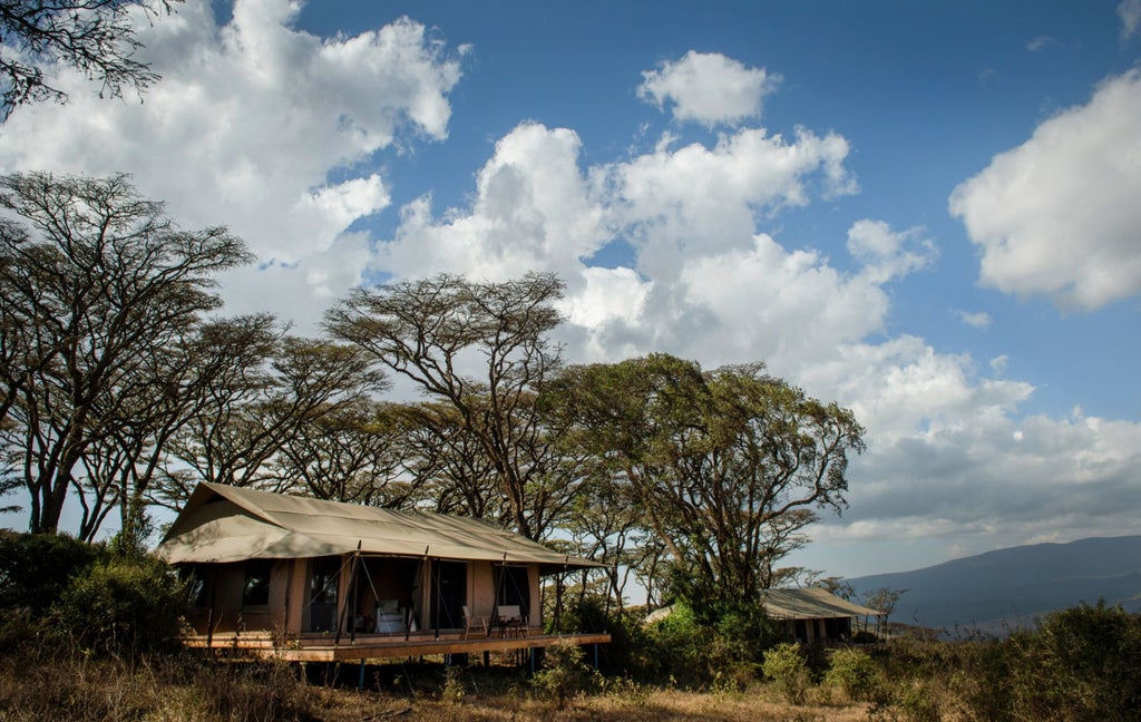 Luxurious safari tent perched on Ngorongoro Crater rim at sunset, with canvas walls, wooden deck and sweeping savanna views