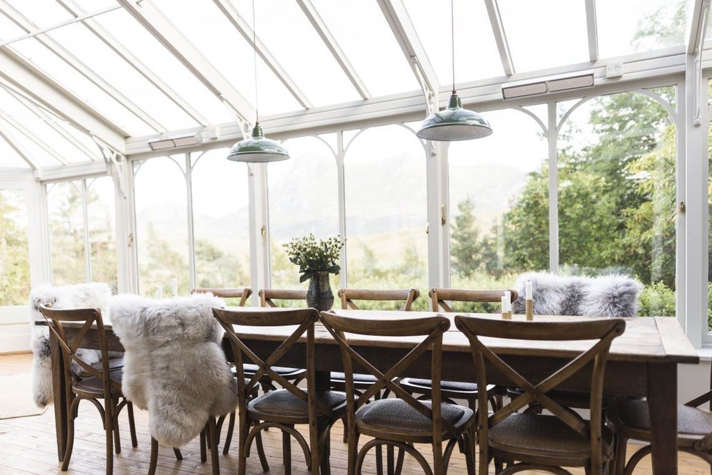 Historic stone Scottish manor house with elegant bay windows, set against rugged Isle of Skye mountains and surrounded by manicured gardens