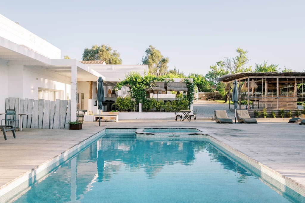 Luxurious Portuguese countryside retreat with traditional wooden veranda, stone walls, and elegant outdoor seating overlooking lush green landscape at sunset