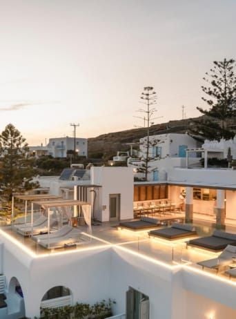 Luxurious white-washed hotel overlooking the azure Aegean Sea, with minimalist design and elegant infinity pool framed by traditional Cycladic architecture in Mykonos.