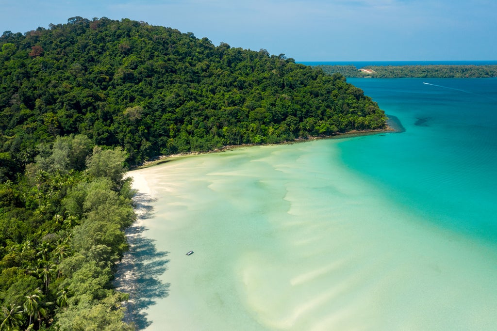 Luxurious overwater villa at Soneva Kiri resort with wooden walkways, turquoise ocean views, and lush tropical forest backdrop in Thailand