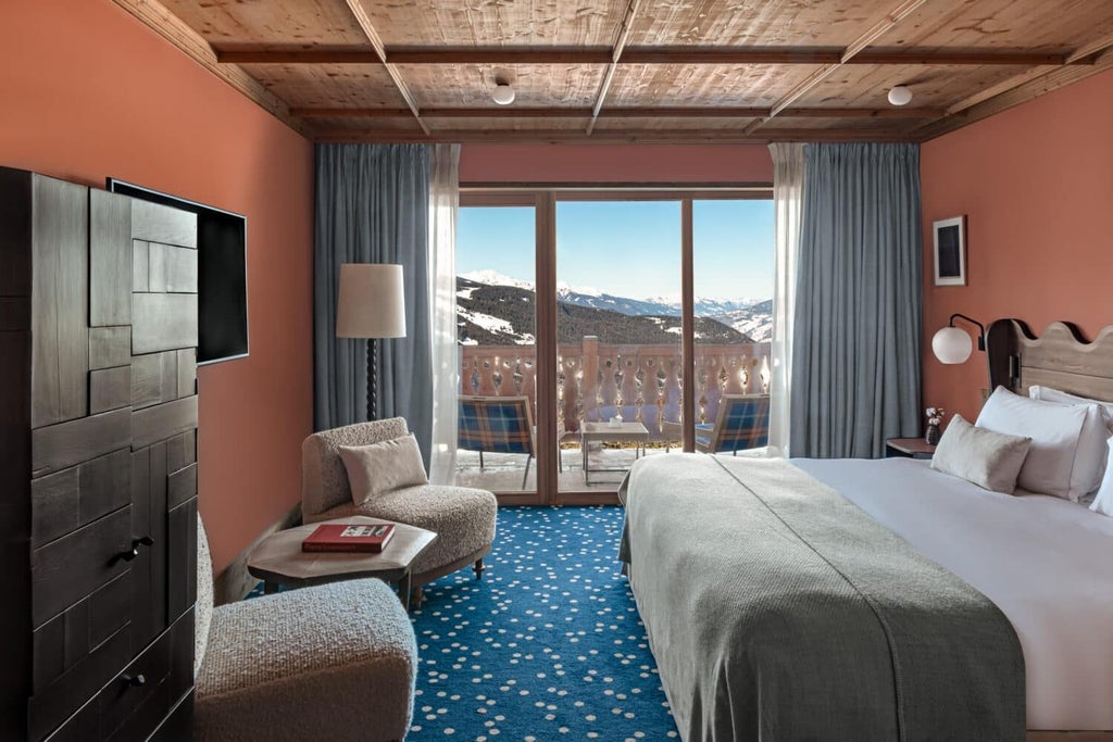 Luxurious deluxe hotel room with alpine-inspired design, wooden accents, plush white bedding, and panoramic mountain view in Méribel, France