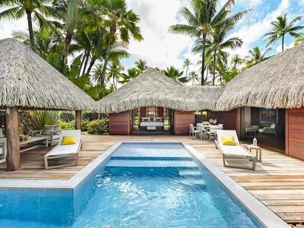 Luxurious overwater villa with private pool overlooking turquoise lagoon, thatched roof, wooden deck, and panoramic Polynesian views