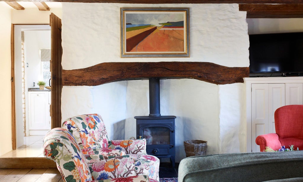 Elegant stone-walled hotel room with plush white bedding, antique wooden furniture, and soft thyme-green accents in a charming UK countryside setting