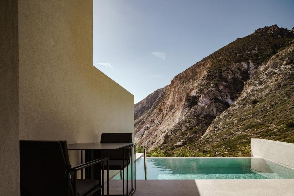 Elegant infinity pool overlooking Aegean Sea at Milos Cove resort, with minimalist sun loungers and panoramic coastal views at sunset