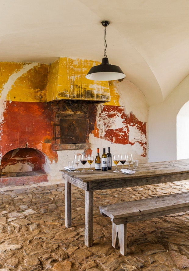 Stone-built luxury Portuguese farmhouse hotel with white walls, terracotta roof tiles and climbing vines set against rolling countryside hills