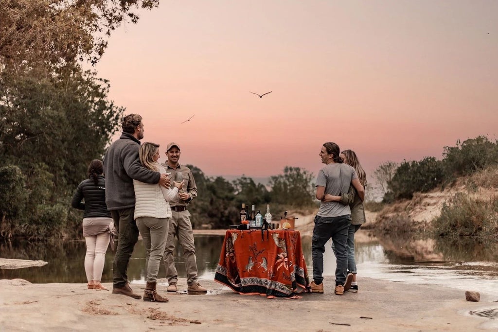 Elegant safari lodge overlooking African bushveld, featuring thatched roof suite with private deck and plunge pool amid acacia trees