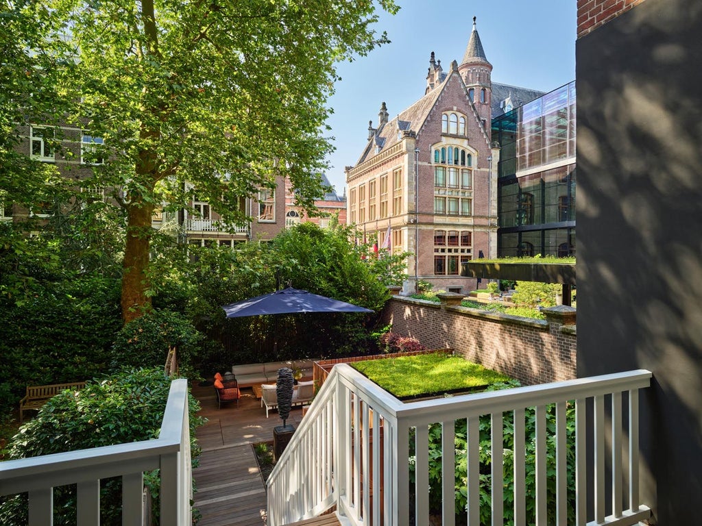 Spacious two-bedroom suite with elegant design, natural light, modern furnishings, and panoramic garden views in prestigious Conservatorium Hotel, Amsterdam.