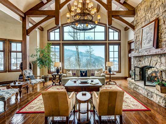 Elegant mountain lodge resort exterior with stone facade, timber beams and snow-capped peaks in Park City's upscale district