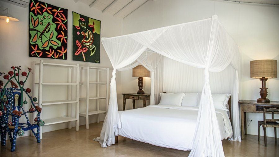 Luxurious rustic Brazilian hotel room with wooden furnishings, warm lighting, and elegant tropical design at UXUA Casa Hotel and Spa in Trancoso, Bahia