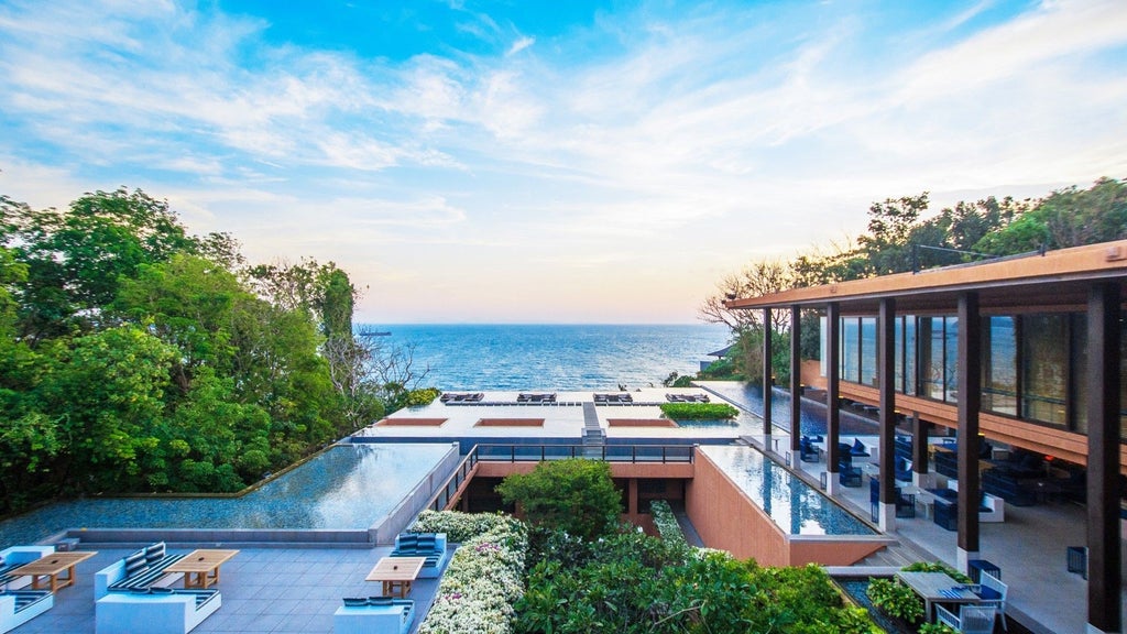 Luxurious infinity pool overlooking Andaman Sea at sunset, with modern loungers and tropical palm trees framing panoramic ocean views