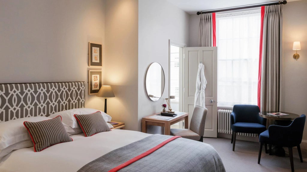 Elegant classic hotel room with vintage wooden furnishings, crisp white linens, and soft ambient lighting in a historic United Kingdom banking establishment.