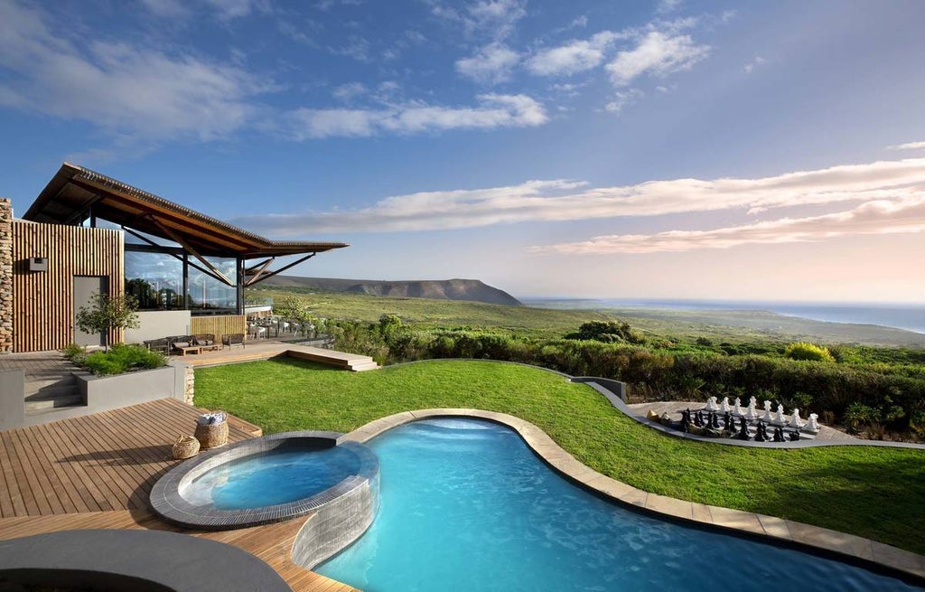 Luxurious lodge suite with floor-to-ceiling windows overlooking the South African bush, featuring modern furniture and expansive deck views