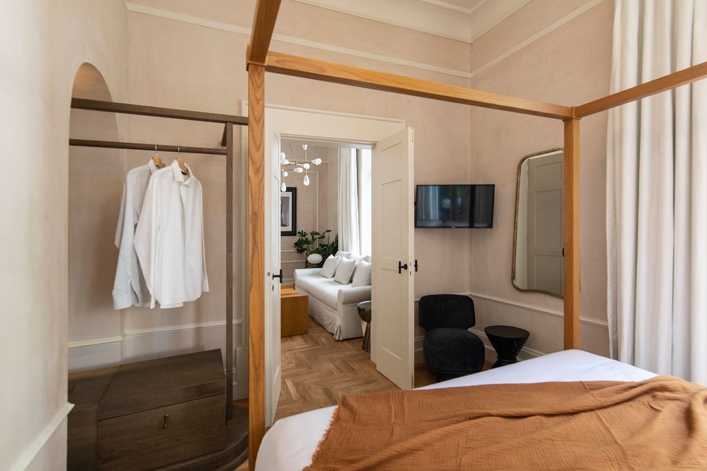 Elegant white-facade boutique hotel in Athens with traditional Greek architecture, wrought-iron balconies, and blooming bougainvillea