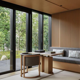 Modern Japanese luxury hotel nestled in Kyoto forest with stone pathways, lantern lighting and traditional pavilion architecture