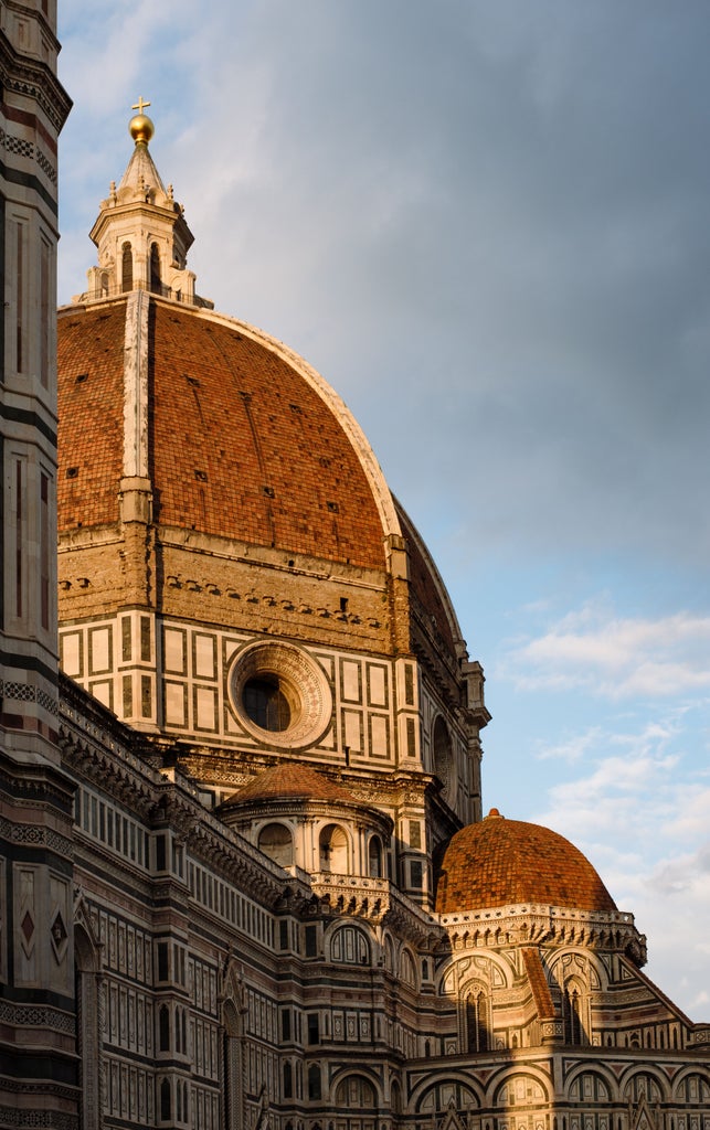 Group of tourists strolling through charming cobblestone streets of Florence, with the iconic Duomo cathedral dome visible in background