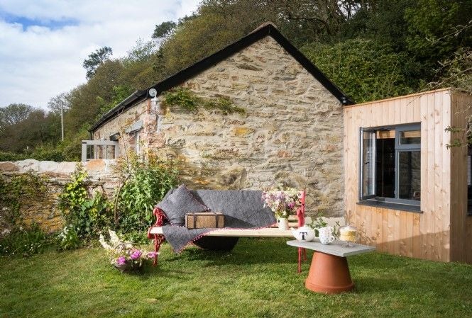 Elegant 18th-century stone cottage with manicured gardens, featuring white-framed windows, climbing ivy, and classic British architecture